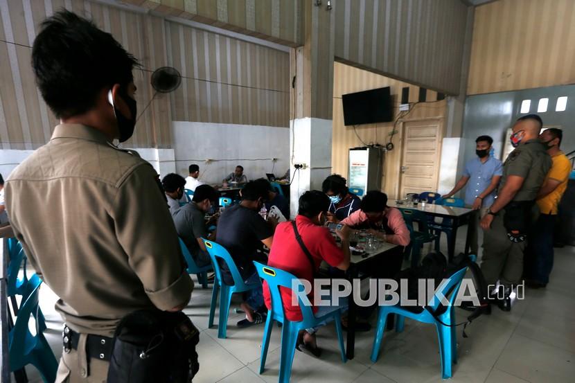 Personel Satpol PP yang tergabung dalam tim gugus tugas percepatan penanganan Covid-19 Ulee Kareng memberikan pengarahan kepada pengunjung warung kopi (warkop) untuk memakai masker dan jaga jarak saat razia penertiban protokol kesehatan di Banda Aceh (ilustrasi)