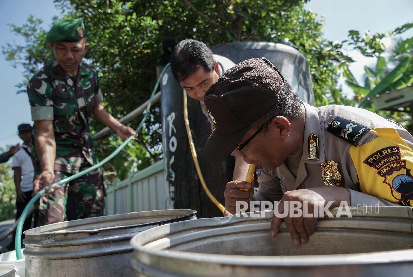 Personel TNI dan Polri membantu mengalirkan air dari bak penampungan ke ember warga saat pembagian air bersih.