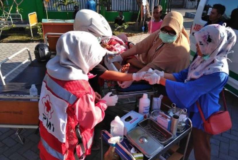 Personil Palang Merah Indonesia sedang mengobati korban selamat gempa bumi lombok