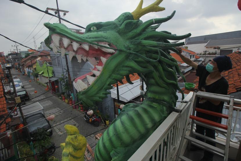 Perupa mengecat patung Naga di kampung pecinan Jalan Kapasan Dalam,Kota  Surabaya, Jawa Timur, Rabu (10/2/2021). Patung Naga yang dibuat dengan tinggi sekitar 10 meter itu untuk menyambut perayaan Tahun Baru Imlek 2572.