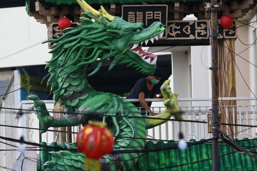 Perupa mengecat patung Naga di kampung pecinan Jalan Kapasan Dalam, Surabaya, Jawa Timur, Rabu (10/2). Kementerian Badan Usaha Milik Negara (BUMN) mengeluarkan surat edaran kepada seluruh BUMN dalam pencegahan penyebaran kasus covid-19 pada libur panjang akhir pekan ini. 