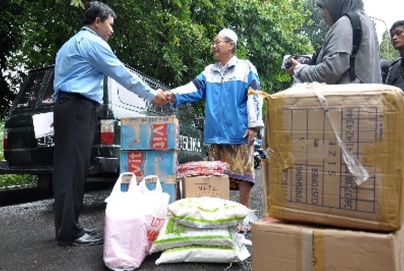 Perwakilan PT. Republika Media Mandiri (kiri) memberikan bantuan secara simbolik kepada pihak panitia Posko komplek kalibata H. Marhusin (kanan) di Posko bencana kelurahan Rawajati,Pancoran, Jakarta Selatan, Kamis (17/1)