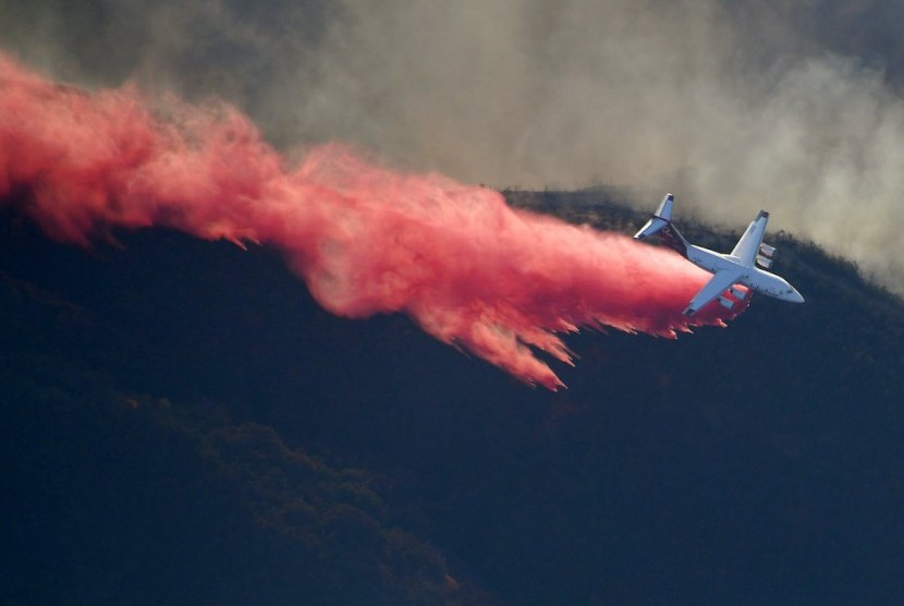 Pesawat menjatuhkan flame retardant atau penghambat nyala untuk memadamkan api yang membakar lahan di Kalifornia, Sabtu (10/11)