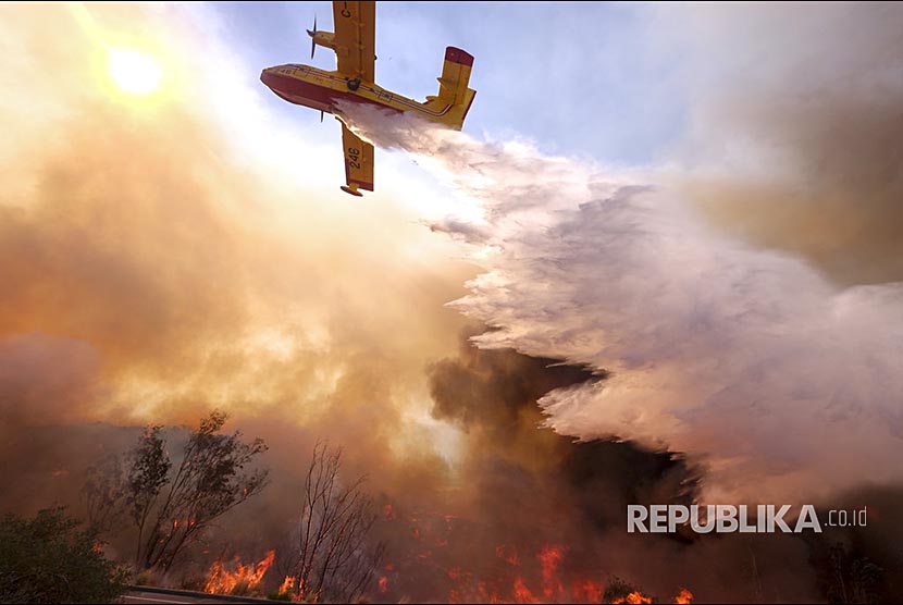 Pesawat pembom air berusaha memadamkan api di jalan Ronald Reagan, Simmi Valley, Kalifornia (12/11) waktu setempat.