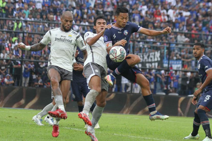 Pesepak bola Arema FC, Dendy Santosa (kanan) berebut bola di udara dengan dua pesepak bola Persib Bandung dalam laga lanjutan BRI Liga 1 di Stadion Kanjuruhan, Kabupaten Malang, Jawa Timur, Ahad (11/9/2022). Persib Bandung mengalahkan Arema FC dengan skor akhir 2-1. 