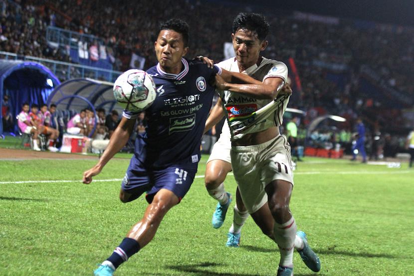 Pesepak bola Arema FC, Dendy Santosa (kiri) berusaha mempertahankan bola dari hadangan pesepak bola Persija Jakarta, Firza Andika (kanan) dalam pertandingan BRI Liga 1 di Stadion Kanjuruhan, Malang, Jawa Timur, Ahad (28/8/2022). 