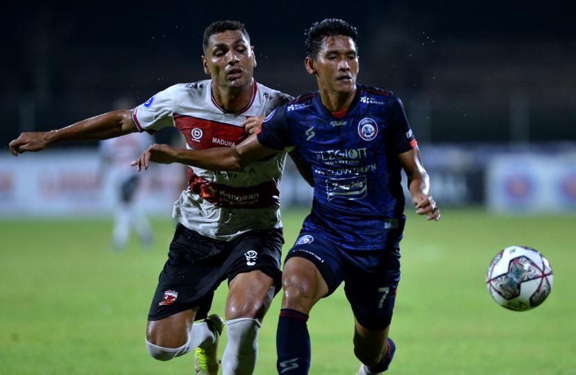 Pesepak bola Arema FC Ryan Kurnia (kanan) berebut bola dengan pesepak bola Madura United Jaimerson Da Silva Xavier (kiri) saat pertandingan Liga 1 di Stadion I Gusti Ngurah Rai, Denpasar, Bali, Jumat (18/2/2022). Madura sudah harus bertanding lagi pada Senin (21/2022).