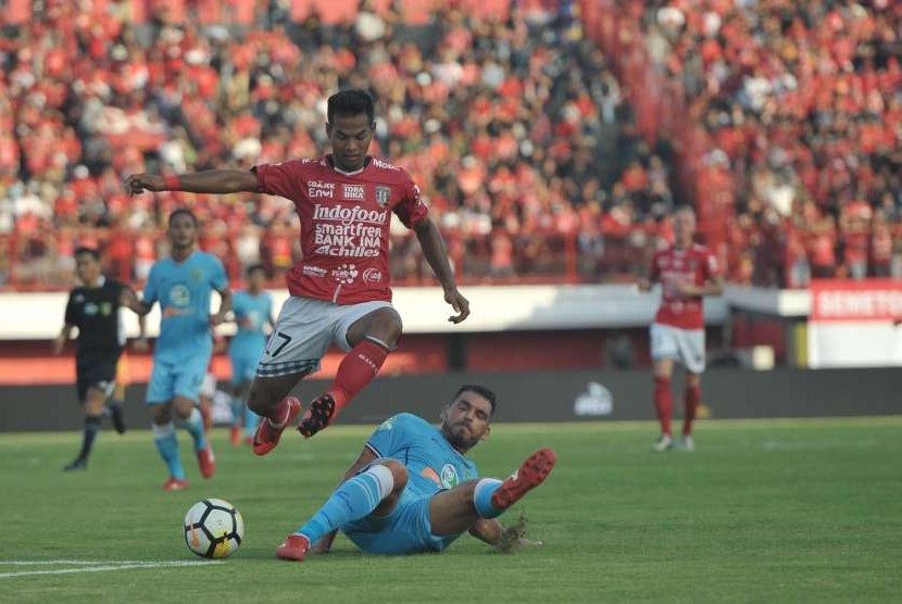 Pesepak bola Bali United Nyoman Sukarja (atas) melewati pesepak bola Persela Lamongan, Wallace Costa (bawah) dalam Pertandingan Sepak Bola Liga 1 2018 di Stadion I Wayan Dipta, Gianyar, Bali, Selasa (11/9).