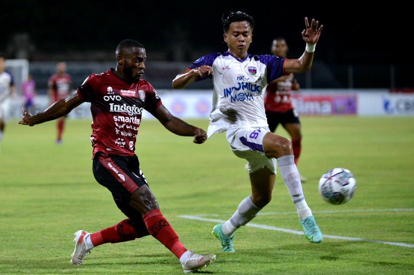 Pesepak bola Bali United Privat Mbarga (kiri) mengumpan bola melewati pesepak bola Persita Tangerang Edo Febriansyah (kanan) saat pertandingan Liga 1 di Stadion I Gusti Ngurah Rai, Denpasar, Bali, Senin (17/1/2022). Bali United kalahkan Persita Tangerang dengan skor 2-0.