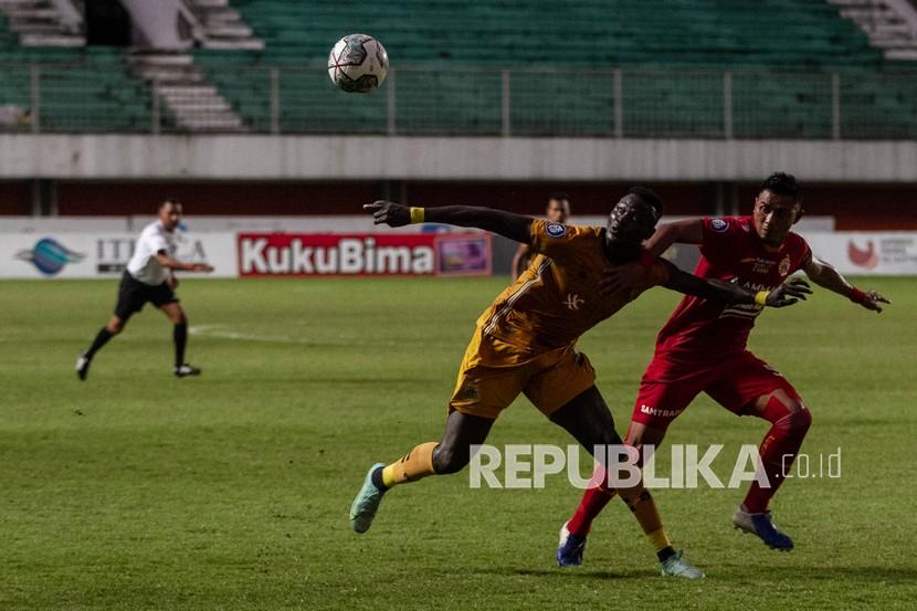 Pesepak bola Bhayangkara FC Ezechiel Ndouasel (kiri) berebut bola dengan pesepak bola Persija Jakarta Maman Abdurahman (kanan) saat pertandingan Liga 1 di Stadion Maguwoharjo, Sleman, DI Yogyakarta, Sabtu (11/12/2021). Pertandingan tersebut berakhir dengan skor 0-0. 