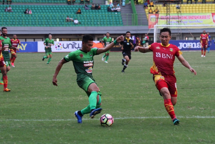 Pesepak bola Bhayangkara FC Lee Yujun (kanan) berusaha menghadang pesepak bola PS TNI Ahmad Nufian Dani (kiri) pada laga Gojek Traveloka Liga 1 di Stadion Patriot Candrabhaga, Bekasi, Jawa Barat, Sabtu (29/4). 