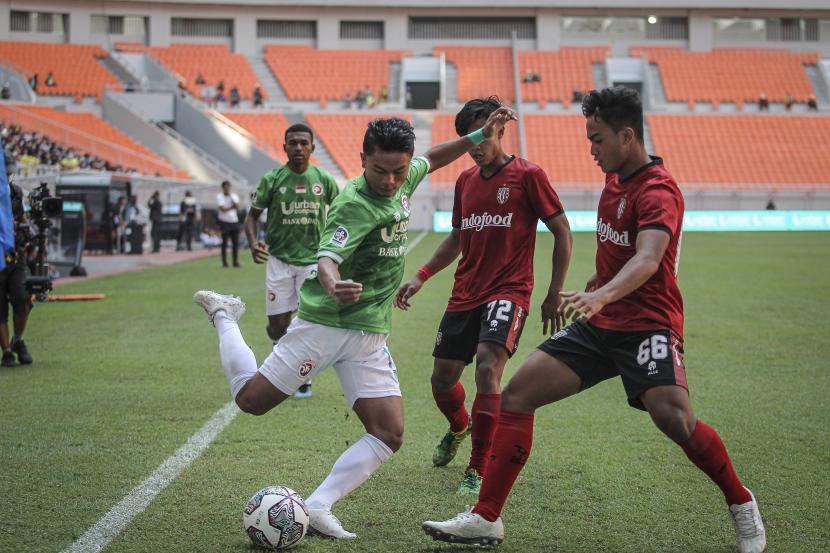 Pesepak bola Indonesia All Stars U-20 Cecep Mulyana (kiri) berebut bola dengan pesepak bola Bali United U-18 I Gede Agus Mahendra (kanan) pada pertandingan International Youth Championship (IYC) 2021 di Jakarta International Stadium, Jakarta, Jumat (15/4/2022). Indonesia All Stars U-20 menang atas Bali United U-18 dengan skor 3-0.