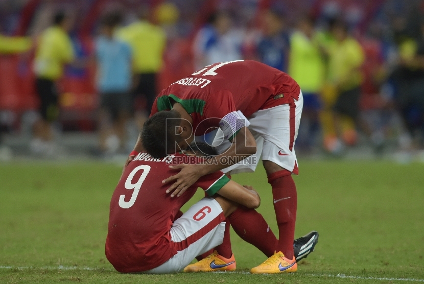 Pesepak bola Indonesia Lestusen Manahati (atas) memeluk Muchlis Hadi Ning Syaifulloh setelah kalah melawan Thailand dalam pertandingan Semifinal Sepak Bola Sea Games ke-28, Sabtu (13/6).(ANTARA FOTO/Nyoman Budhiana)