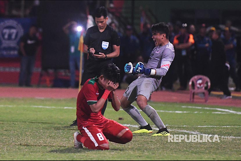 Pesepak bola Indonesia U-19 Witan Sulaeman (kiri) menutup wajahnya ketika gagal memasukkan bola ke gawang timnas Malaysia U-19 saat adu penalti dalam laga semifinal Piala AFF U-19 di Gelora Delta Sidoarjo, Sidoarjo, Jawa Timur, Kamis (12/7). 