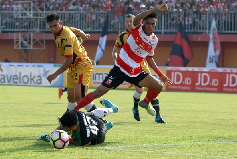 Pesepak bola Madura United (MU) FC Saldi (kanan) berebut bola dengan penjaga gawang Mitra Kukar Gerry Mandagi (bawah) pada laga Liga 1 di stadion Gelora Ratu Pamelingan (SGRP) Pamekasan, Jumat (28/4). 