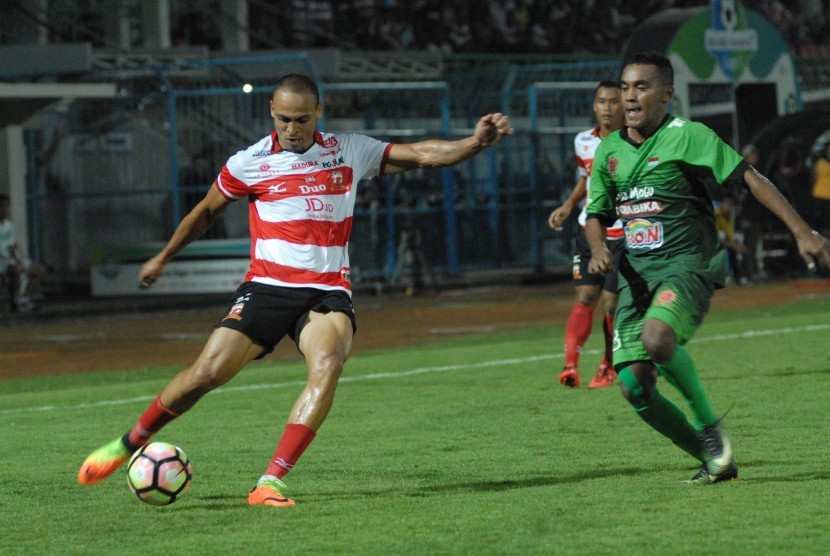 Pesepak bola Madura United (MU) Piter Osaze Odem Wingie (kiri) dibayangi pesepak bola PS TNI Mohammad Kasim Slamat (kanan) berusaha menendang bola dalam pertandingan kompetisi Liga 1 di Stadion Gelora Bangkalan, Bangkalan, Jawa Timur, Jumat (19/5).