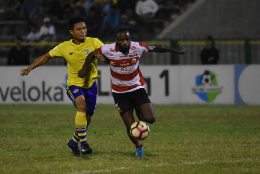 Pesepak bola Persegres Gresik United Ade Suhendra (kiri) menghadang laju pesepak bola Madura United FC Greg Nwokolo (kanan) dalam laga lanjutan Gojek Traveloka Liga 1 di Stadion Petrokimia Gresik, Jawa Timur, Selasa (26/9). Persegres Gresik United dikalahkan Madura United FC dengan skor 0-3.