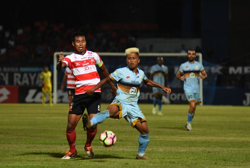 Pesepak bola Persela Lamongan Moch. Fahmi Al-Ayyubi (kanan) berebut bola dengan pesepak bola Madura United FC Munhar (kiri) dalam pertandingan Gojek Traveloka Liga 1 di Stadion Surajaya Lamongan, Jawa Timur, Jumat (21/4). 