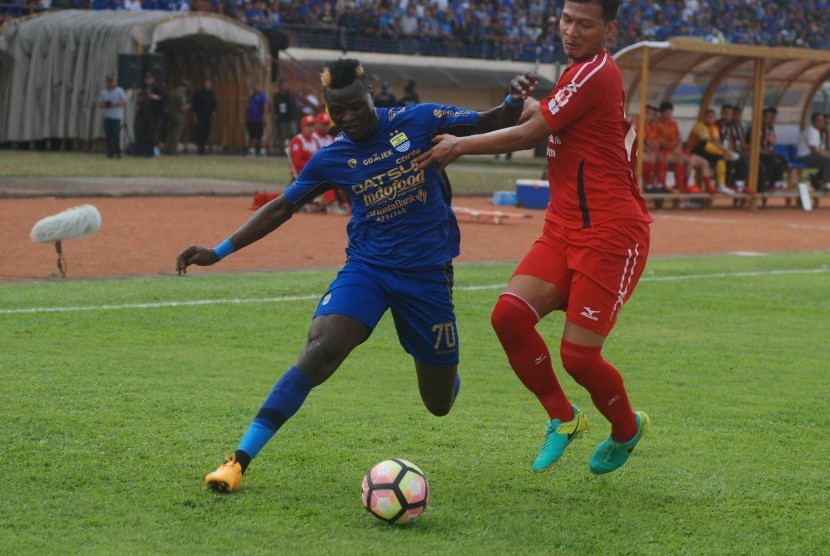 Pesepak bola Persib Bandung Ezechiel Ndouasel (kiri) berebut bola dengan pesepak bola Semen Padang FC Agung Prasetyo (kanan) pada laga lanjutan Liga 1 di Stadion Si Jalak Harupat Soreang, Kabupaten Bandung, Jawa Barat, Sabtu (9/9). 