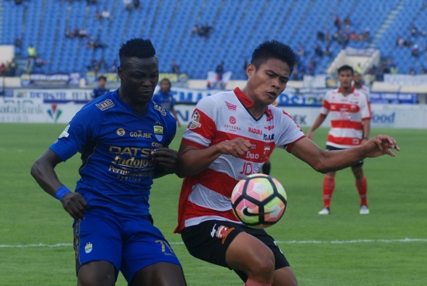 Pesepak bola Persib Bandung Ezechiel Ndouasel (kiri) berebut bola dengan pesepak bola Madura United FC Fachrudin Wahyudi Aryanto (kanan) pada laga lanjutan GO-JEK Traveloka Liga 1 di Stadion Si Jalak Harupat Soreang, Kabupaten Bandung, Jawa Barat, Kamis (19/10). 