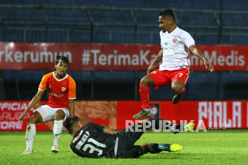 Pesepak bola Persija Jakarta Ramdani Lestaluhu (kanan) melompati tubuh penjaga gawang Borneo FC Samarinda, Gianluca Claudio Pandeynuwu (bawah) dalam pertandingan Piala Menpora Grup B di Stadion Kanjuruhan, Malang, Jawa Timur, Sabtu (27/3/2021). Persija menang atas Borneo FC Samarinda dengan skor akhir 4-0. 