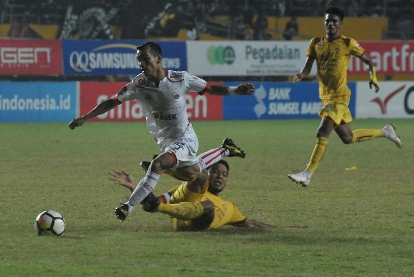 Pesepak bola Persija Jakarta Riko Simanjuntak (kiri) berebut bola dengan pesepak bola Sriwijaya FC Hamka Hamzah (bawah) pada pertandingan Liga 1 di Stadion Gelora Sriwijaya Jakabaring Palembang, Sumatera Selatan, Selasa (10/7). Sriwijaya FC bermain imbang bersama Persija dengan skor 2-2.