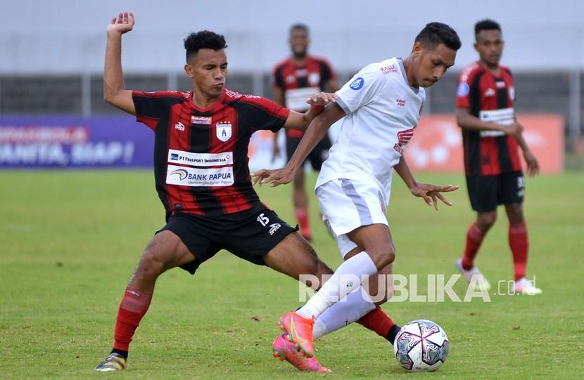 Pesepak bola Persipura Jayapura Theo Fillo (kiri) berebut bola dengan pesepak bola PSM Makassar Delfin Rumbino (kanan) saat pertandingan Liga 1 di Stadion Kompyang Sujana, Denpasar, Bali, Kamis (10/3/2022). Persipura Jayapura bermain imbang lawan PSM Makassar dengan skor 0-0. 