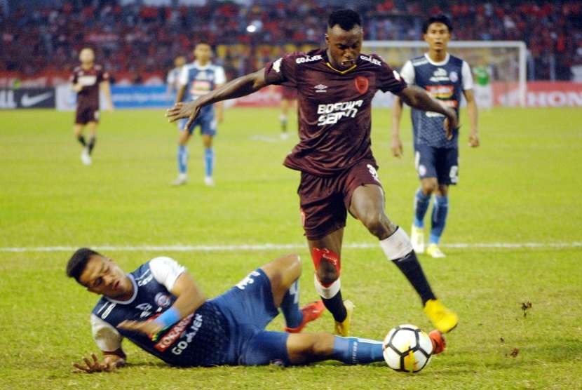 Pesepak bola PSM Makassar Nke Ondoua Guy Junior (kanan) berebut bola dengan pesepak bola Arema FC M Rafli (kiri) dalam lanjutan Liga 1 di Stadion Andi Mattalatta, Makassar, Sulawesi Selatan, Minggu (14/10). Tuan rumah PSM Makassar menang melawan Arema FC dengan skor 2-1 (1-0)