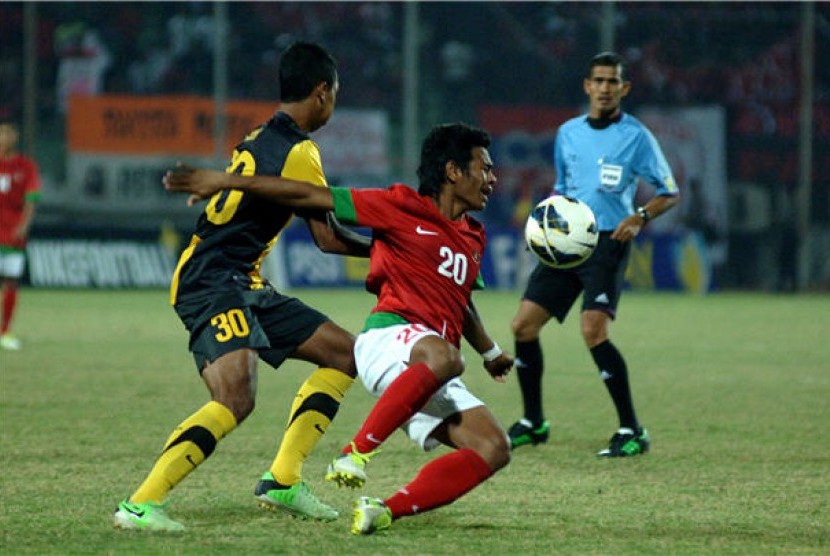 Pesepak bola tim nasional Indonesia, Ilham udin Armaiyn (kanan), berebut bola dengan pesepak bola timnas Malaysia, Adam Nor Bin Azlin, dalam pertandingan babak kualifikasi Grup B AFF U-19 Championship 2013 di Gelora Delta Sidoarjo, Jawa Timur, Rabu (18/9) 