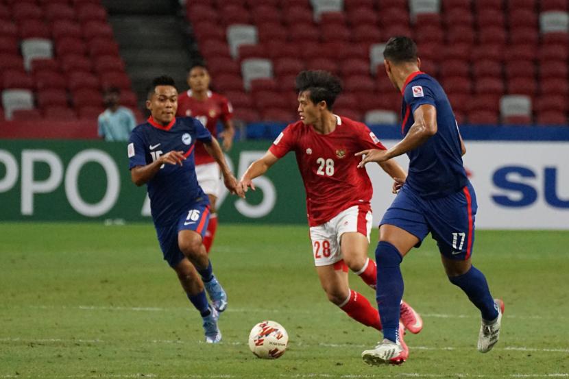 Pesepak bola Timnas Indonesia Alfreanda Dewangga (tengah) berusaha masuk ke pertahanan lawan dengan dibayangi pesepak bola Timnas Singapura Hami Syahin (kiri) dalam pertandingan Semi Final Leg 2 Piala AFF 2020 di National Stadium, Singapura, Sabtu (25/12/2021). 