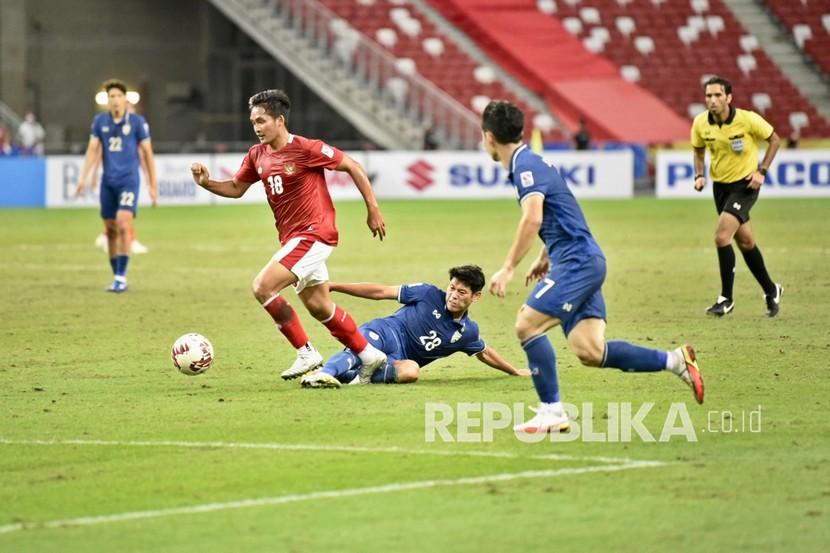 Pesepak bola Timnas Indonesia I Kadek Agung (kedua kiri) menggiring bola dengan dikawal pesepak bola Timnas Thailand Pokklaw A-Nan (tengah) dalam pertandingan Babak Final Leg 1 Piala AFF 2020 di National Stadium, Singapura, Rabu (29/12/2021). Indonesia kalah dengan skor 0-4. 