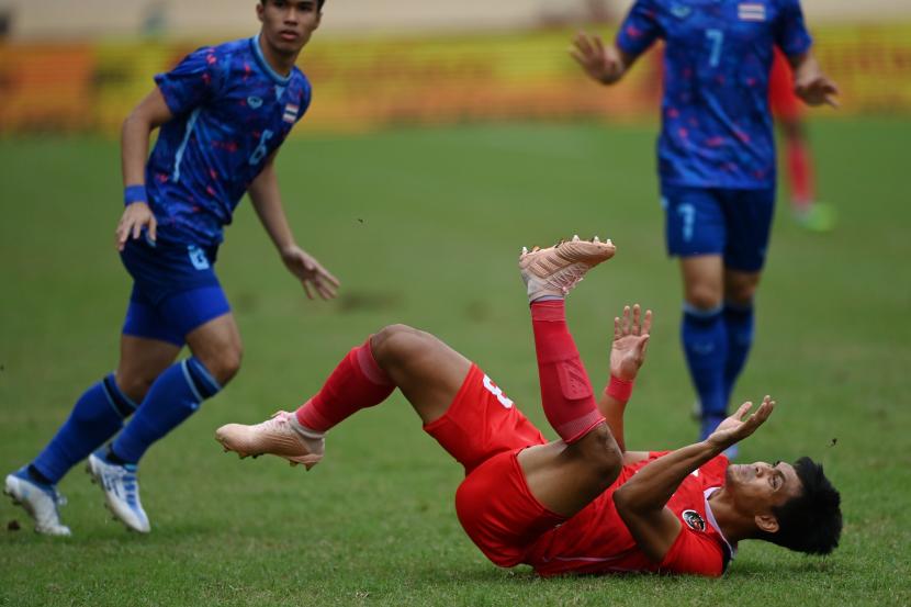 Pesepak bola Timnas Indonesia Rachmat Irianto (kanan) terjatuh usai berebut bola dengan sejumlah pesepak bola Timnas Thailand dalam pertandingan semifinal sepak bola SEA Games 2021 Vietnam di Stadion Thien Truong, Nam Dinh, Vietnam, Kamis (19/5/2022).
