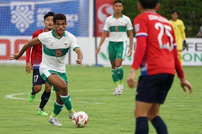 Pesepak bola Timnas Indonesia Ricky Kambuaya (kiri) berusaha melewati hadangan pesepak bola Timnas Laos Loungleuang Keophouvong (kanan) saat babak pertama pertandingan grup B Piala AFF 2020 di Stadion Bishan, Singapura, Ahad (12/12/21). Timnas Indonesia berhasil mengalahkan Laos 5-1.