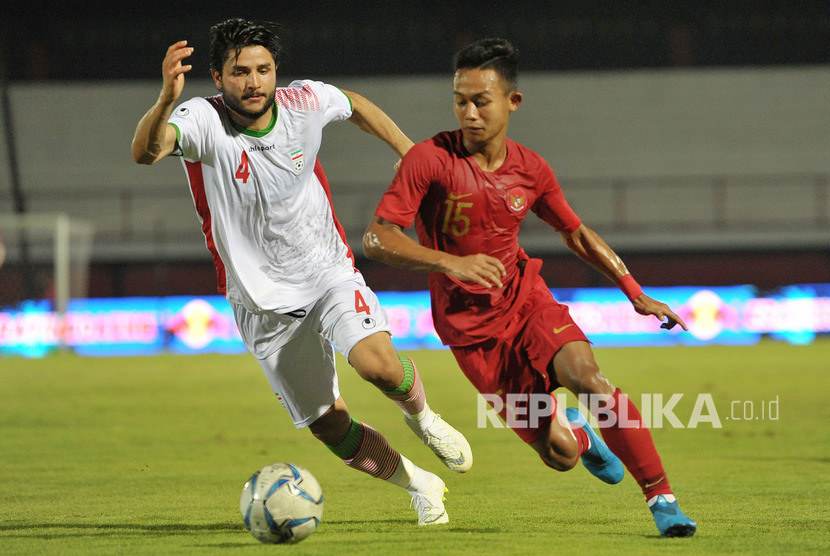 Pesepak bola timnas Indonesia U-22 Sani Rizki Fauzi (kanan) menggiring bola dengan dibayangi pesepak bola Timnas Iran U-23 Aref Gholami pada pertandingan sepak bola persahabatan di Stadion I Wayan Dipta, Gianyar, Bali, Rabu (13/11/2019).