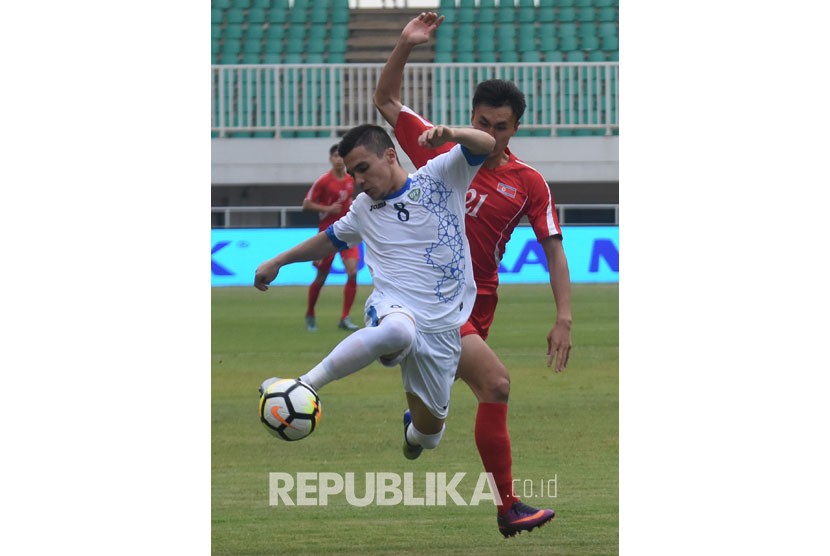 Pesepak bola timnas U-23 Uzbekistan Kenjabaev Islom (kiri) berebut bola dengan pesepak bola timnas U-23 Korea Utara Kim Nam Il pada laga perdana PSSI Anniversary Cup 2018 di Stadion Pakansari, Bogor, Jawa Barat, Jum'at (27/4). 