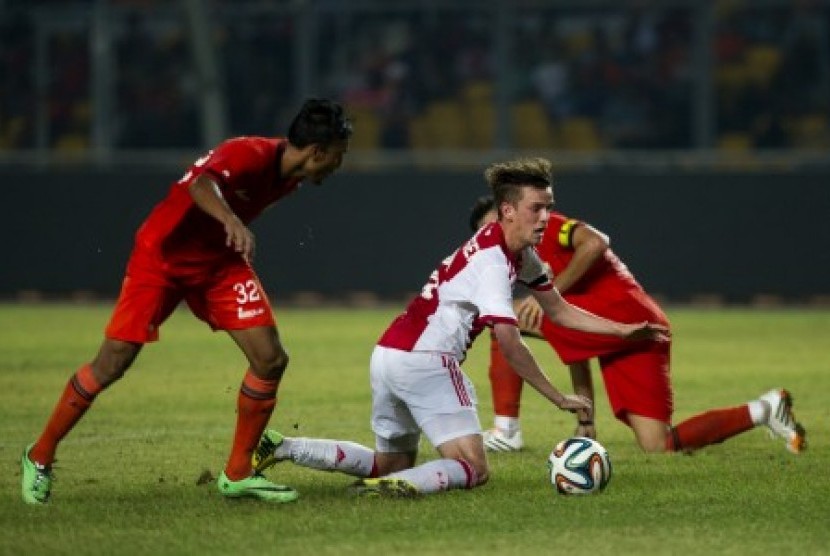 Pesepakbola Ajax Amsterdam, Lucas Andersen (tengah), terjatuh ketika berusaha melewati hadangan pesepakbola Persija Jakarta, saat laga persahabatan di Stadion Utama Gelora Bung Karno, Senayan, Jakarta, Ahad (11/5) malam. Tim tuan rumah Persija takluk dari 