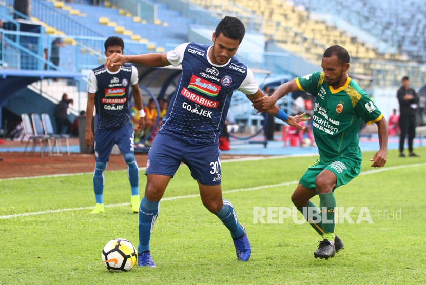 Pesepakbola Arema FC, Muhammad Rafli (kiri) berusaha mempertahankan bola dari hadangan pesepakbola Sriwijaya FC, Muhammad Nur Iskandar (kanan) dalam pertandingan Liga I GOJEK di Stadion Kanjuruhan, Malang, Jawa Timur, Ahad (9/12/2018).