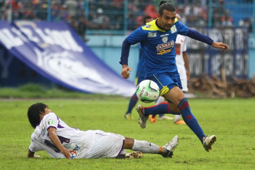 Pesepakbola Arema Indonesia Cronous, Gustavo Lopez (atas) melompat untuk menghindari hadangan pesepakbola Persik Kediri, Tamsil (bawah) dalam pertandingan Piala Gubernur Grup B di Stadion Kanjuruhan, Malang, Jawa Timur, Jumat (20/12). Arema menjadi juara g