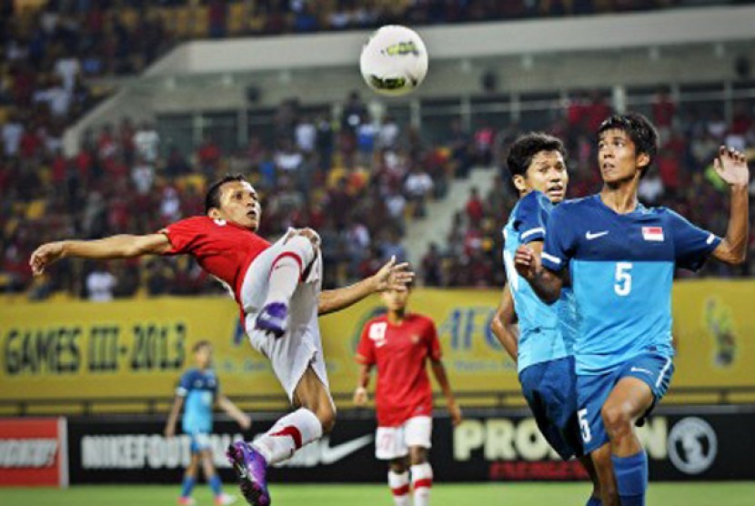 Pesepakbola Indonesia Hendra Adi Bayauw (kiri) berebut bola dengan pesepakbola Singapura Ali Hudzaifi (kanan) dalam pertandingan babak kualifikasi grup E Piala Asia (AFC) U-22 di Stadion Utama Riau, Pekanbaru, Riau, Ahad (15/7)  