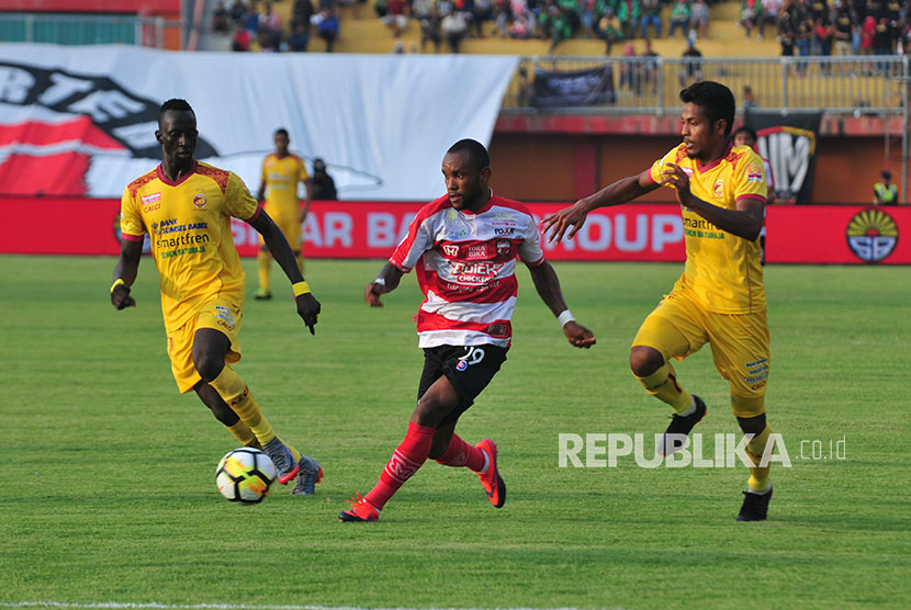 Pesepakbola Madura United (MU) Zah Rahan (tengah) berusaha melewati pesepak bola Sriwijaya FC Konate Makan (kiri) dan Zulfiandi (kiri) dalam kompetisi Go-Jek Liga 1 di Stadion Gelora Ratu Pamelingan (SGRP) Pamekasan, Jawa Timur, Sabtu (7/4).