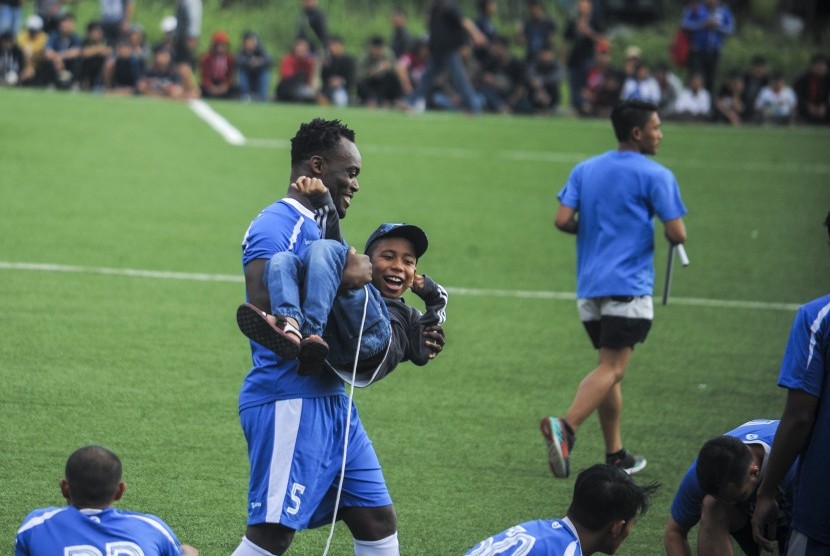 Pesepakbola Persib, Michael Essien menggendong seorang anak sebelum mengikuti latihan rutin di Lapangan Lodaya, Bandung, Jawa Barat, Jumat (31/3). Essien berstatus marquee player pada Liga 1 Indonesia.