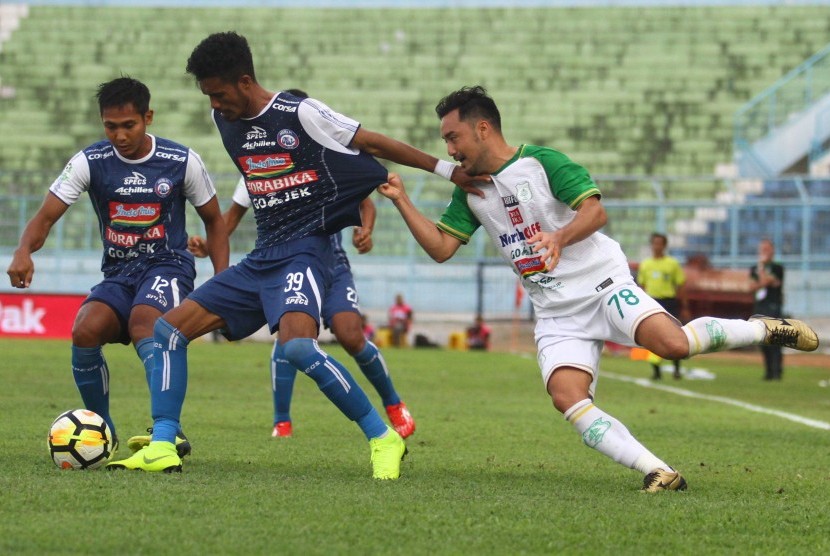 Pesepakbola PSMS Medan, Shohei Matsunaga (kanan) berusaha merebut bola dari pesepakbola Arema FC, Alfin Tuasalamony (tengah), dalam pertandingan Liga I GOJEK di Stadion Kanjuruhan Malang, Ahad (28/10/2018).