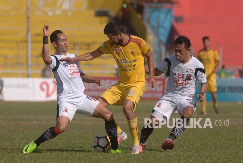 Pesepakbola Sriwijaya FC Manuchehr Jalilov (tengah) berebut bola dengan dua pemain Madura United FC pada pertandingan lanjutan Gojek Liga1 di Stadion GOR H Agus Salim, Padang, Sumatera Barat, Sabtu (11/8).