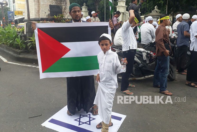 Peserta Aksi Bela Palestina dari Pemuda Pasar Kliwon meginjak bendera Israel sambil membentangkan bendera Palestina. Hal ini sebagai bentuk kekesalan atas agresi militer Israel yang semakin meningkat pasca pernyataan Presiden Amerika Donald Trump pada Jumat (15/12). 
