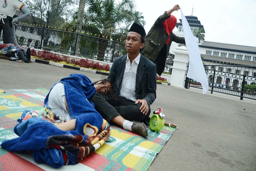  Peserta aksi dari Komunitas Gerbong Bawah Tanah melakukan teaterikal menggambarkan pejabat yang menidurkan hak politik rakyat pada aksi menolak UU Pilkada, di depan Gedung Sate, Kota Bandung, Rabu (1/10).(Republika/Edi Yusuf ).