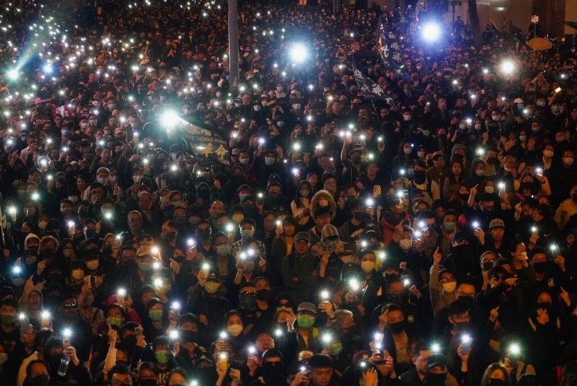 Peserta aksi Hong Kong menyalakan senter dari smartphone mereka saat berkumpul di jalanan Hong Kong, Ahad (8/12). Enam bulan berlalu, aksi demonstrasi Hong Kong masih berlangsung.