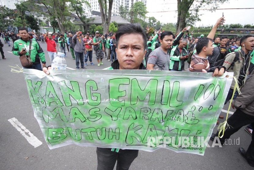 Peserta aksi membawa berbagai poster dan spanduk pada aksi ribuan pengemudi transportasi berbasis aplikasi online di depan Gedung Sate, Kota Bandung, Senin (16/10).