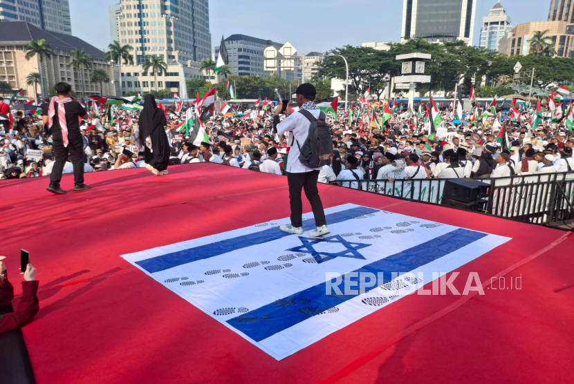 Peserta aksi menginjak bendera Israel di depan Patung Kuda, Silang Monas, Jakarta, Ahad (12/10/2025).
