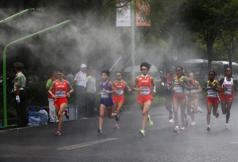 Peserta berlari melintasi jalur berkabut dalam lomba maraton Kejuaraan Dunia IAAF Beijing 2015 di National Stadium alias Bird Nest di Beijing, China, 30 Agustus 2015.