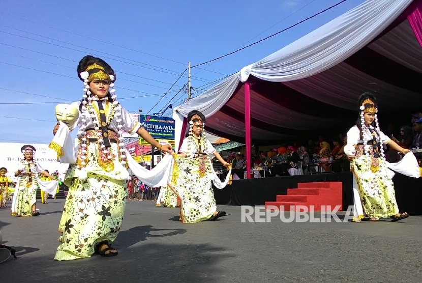 Peserta karnaval membawakan sosok topeng panji pada acara The Caruban Carnival.